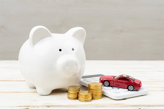 Piggy bank with toy car and stacked coins representing affordable car purchasing and car budget.
