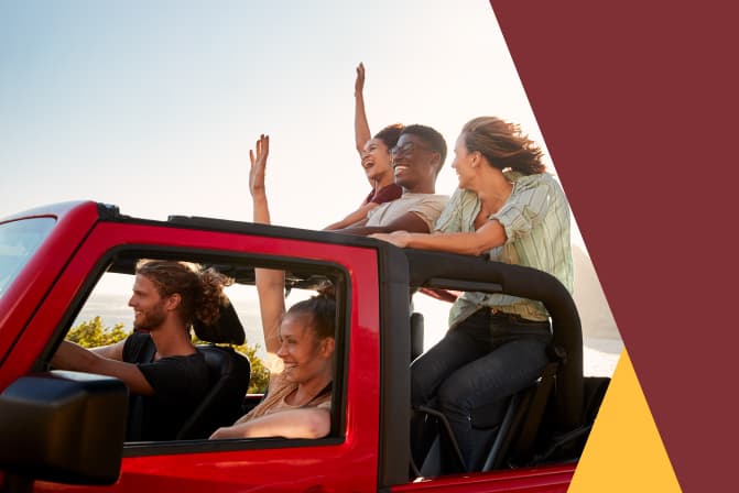 two young women and a young man sitting in a jeep