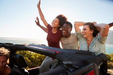 Happy friends enjoying a summer drive in their used car.