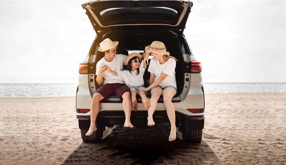 Family enjoying a day at the beach from the trunk of a car.