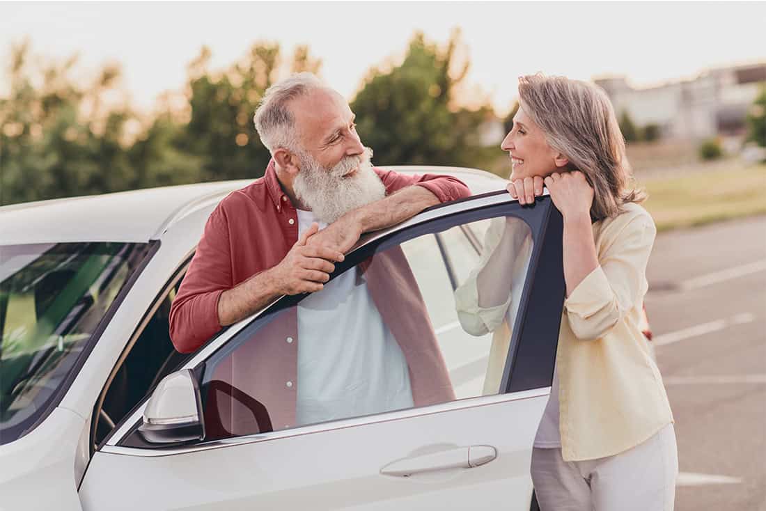 Elderly man and woman enjoying conversation outside a car, having found their dream car.