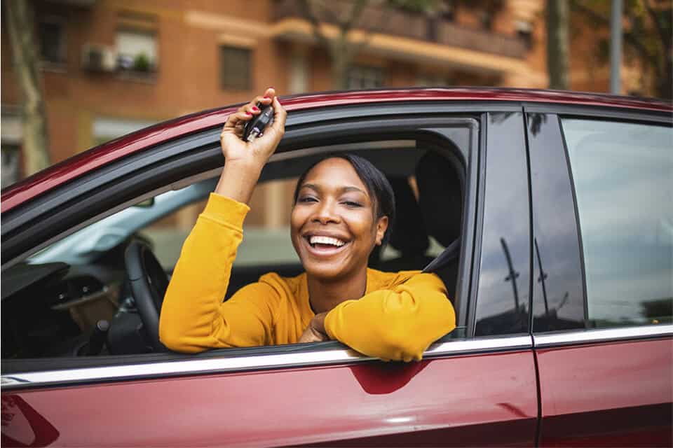 Woman smiling and excited having just leased a new car.