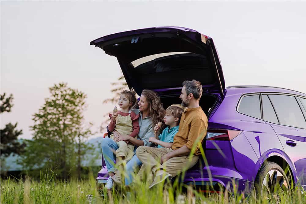 Family adventure with kids and parents near a purple SUV after completing their auto loan purchase.