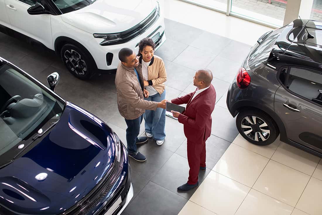 A preferred dealer salesman with members helping them find the best car that fits them.