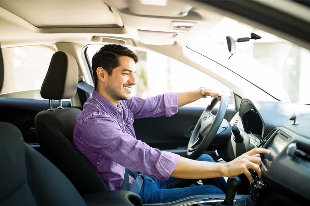 Man driving a vehicle, enjoying a smooth ride, in his used car after completing his purchase with a used auto loan.