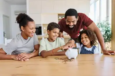 Parents saving coins in a piggy bank with kids as they discuss money management topics during back-to-school season.