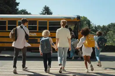 Children and a parent heading back to school by walking towards a school bus.