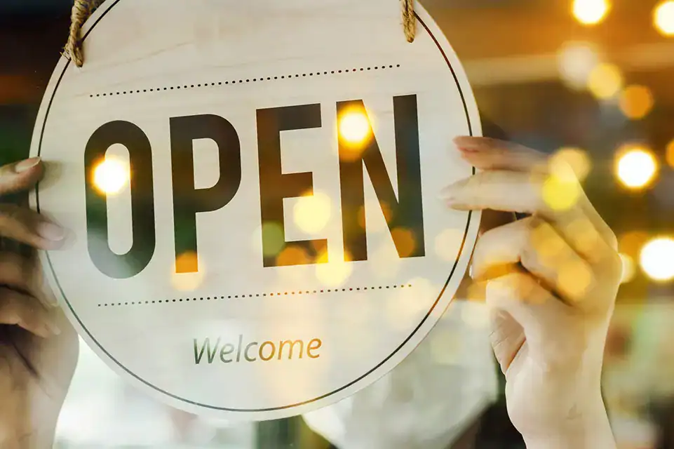 Open sign held by hands, welcoming members to learn more about our business solutions.