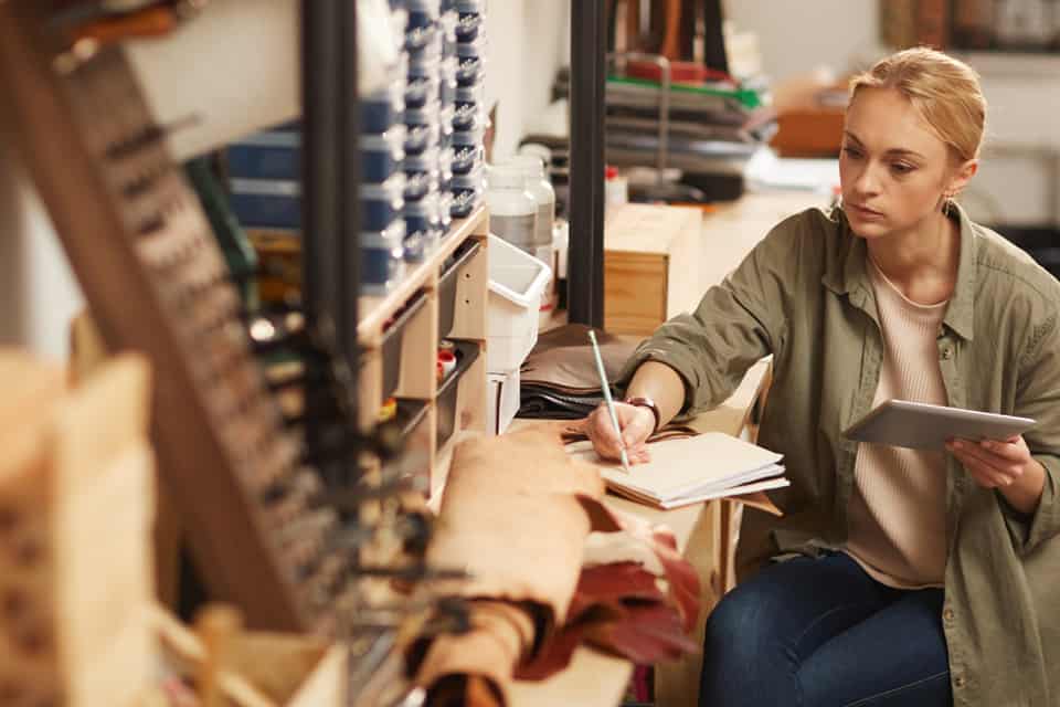 Woman tallies figures on a notepad in her work studio