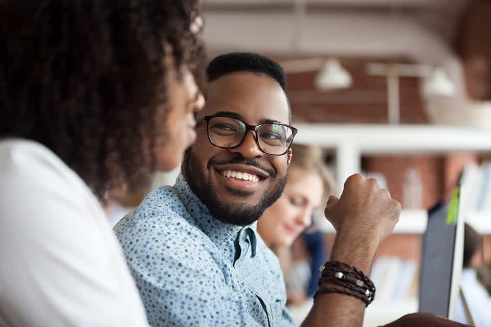 A man looks at his colleague and smiles