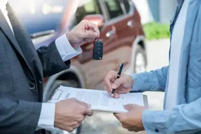 Customer signing paperwork while receiving car keys to a new, used, or leased car.
