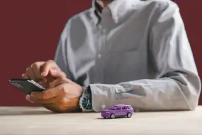 Person using smartphone to learn about whether to sell or trade in their car when looking to buy a new car.