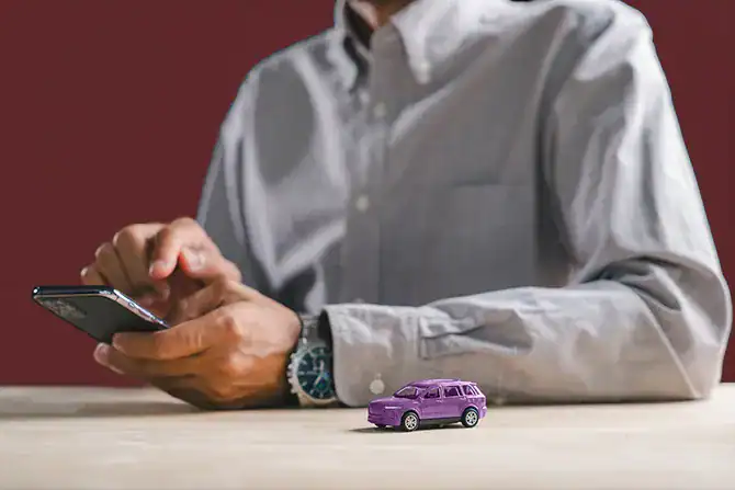 Person using smartphone to learn about whether to sell or trade in their car when looking to buy a new car.