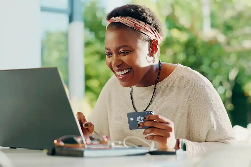 Smiling woman using a credit card and laptop.