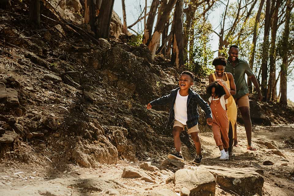 A family with two young children hikes through a forest