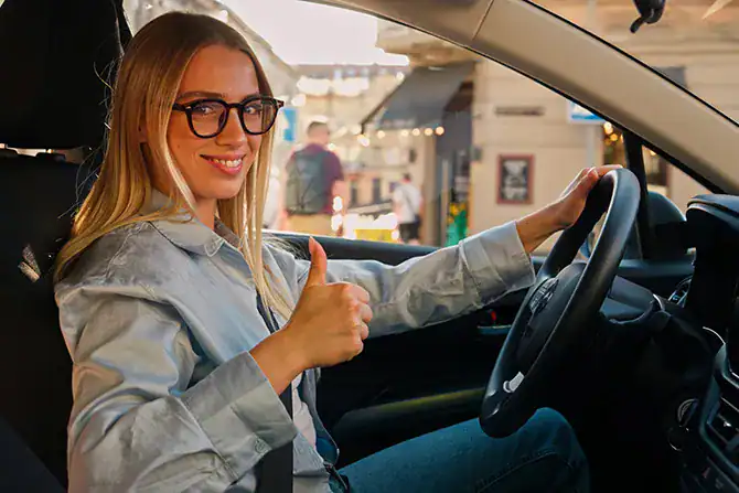 Happy woman driving a car, showing a positive, affordable car-purchasing experience with her credit score.