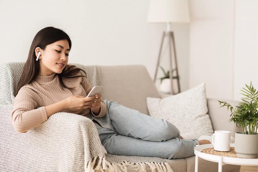Woman using her digital device on a couch.