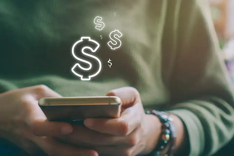 Person using smartphone with dollar sign icons indicating direct deposit.