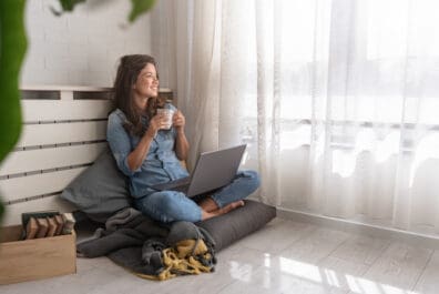 mujer sentada junto a una ventana sosteniendo una taza de café