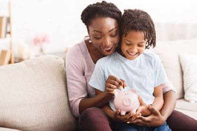 mom and child putting money into a piggy bank