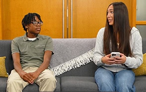 Two people are talking on a sofa, representing youth counseling services.