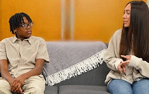 Two individuals having a supportive conversation on a couch.