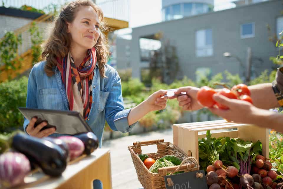A customer pays for produce at a farmer's market using a credit card