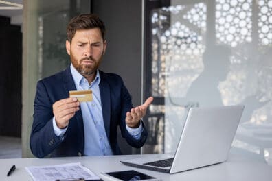 Man looking at credit card with concern that his account was compromised.