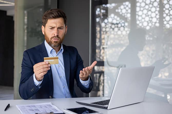 Man looking at credit card with concern that his account was compromised.