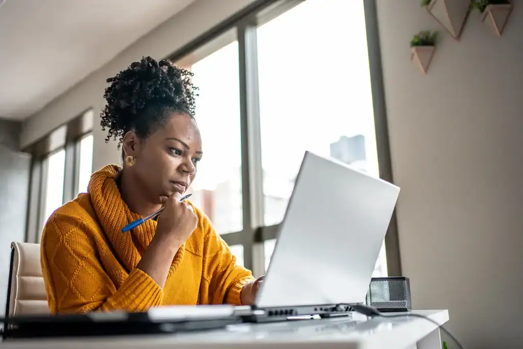 Woman working on a laptop reading up about how to avoid pop up scams.