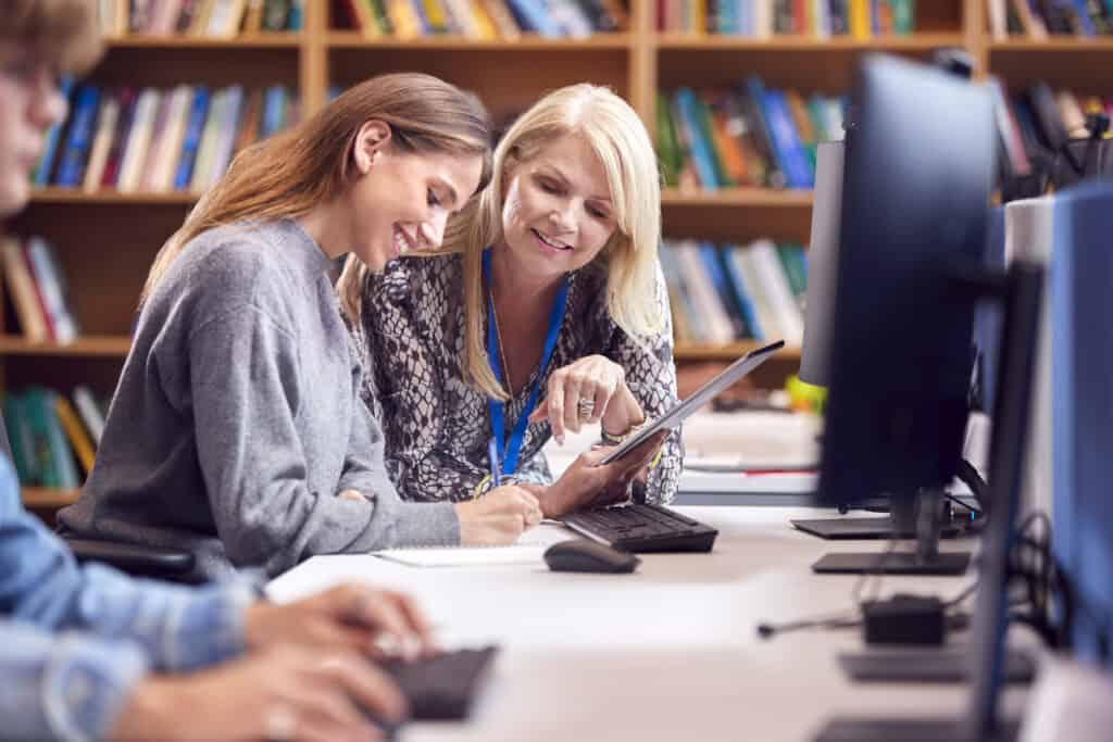 teacher assisting female student