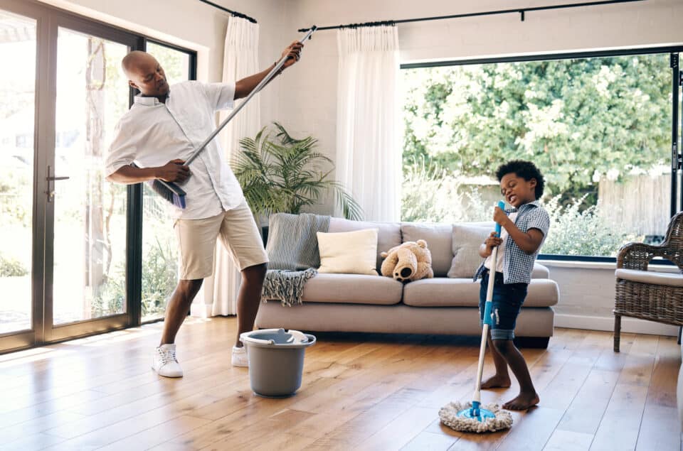 father and son mopping the floor and having fun doing chores. Teach financial awareness through Mind & Money