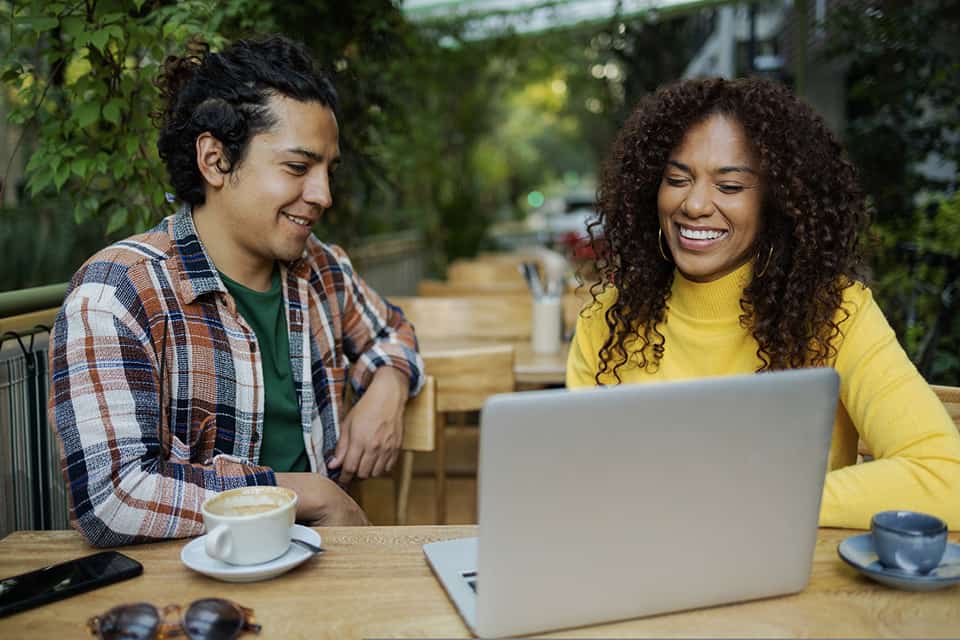 amigos sentados a la mesa en una computadora portátil mirando los beneficios para miembros, Turbotax, boletos para los Milwaukee Bucks