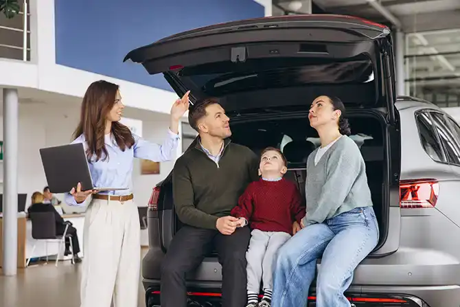 Family receiving car assistance at Educators CU in a dealership setting.