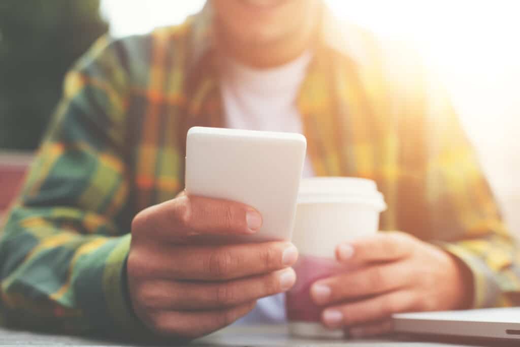 Hombre con teléfono móvil sentado en la cafetería de la calle