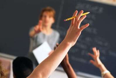 eacher pointing to raised hands in classroom
