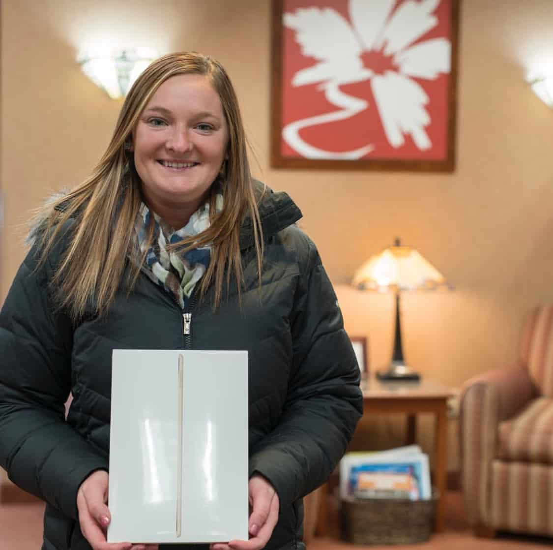 a woman holding a box with an iPad inside