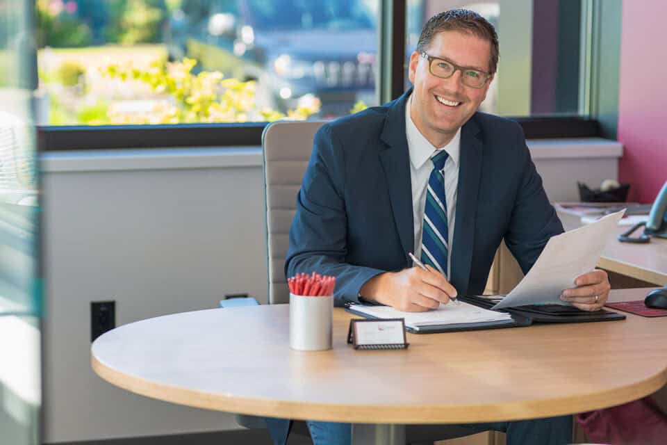 Financial professional from Investment Services in office, smiling and working at desk.