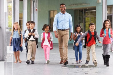 group of children walking down hallway with teacher
