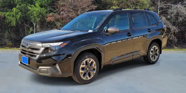 Black SUV parked in a lot with trees in the background.
