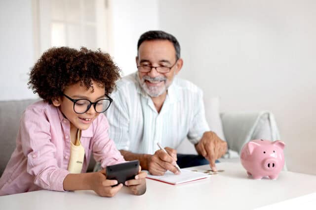 A child and an older man are using a smartphone together at home.