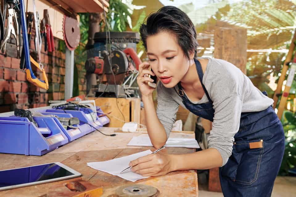 Mujer toma una llamada telefónica de negocios mientras toma notas