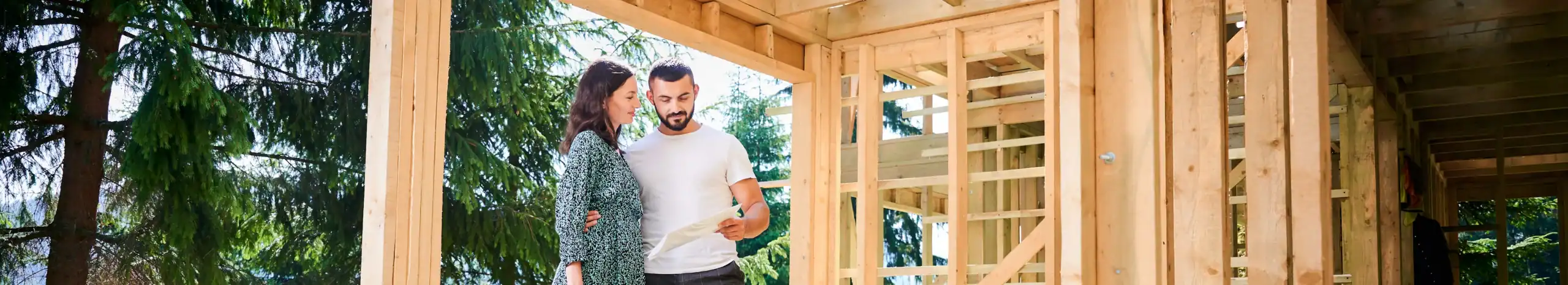 A couple excited about their construction mortgage options, discussing building plans at a construction site.