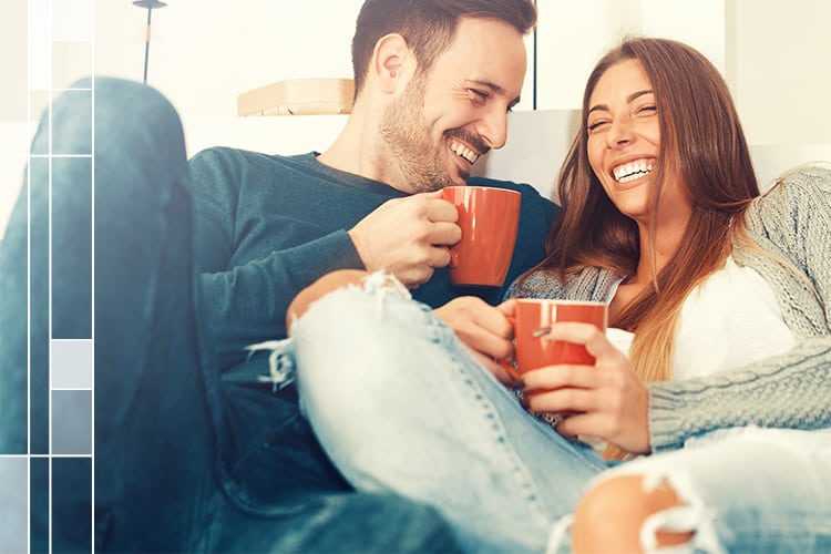 couple sitting next to each other drinking coffee laughing