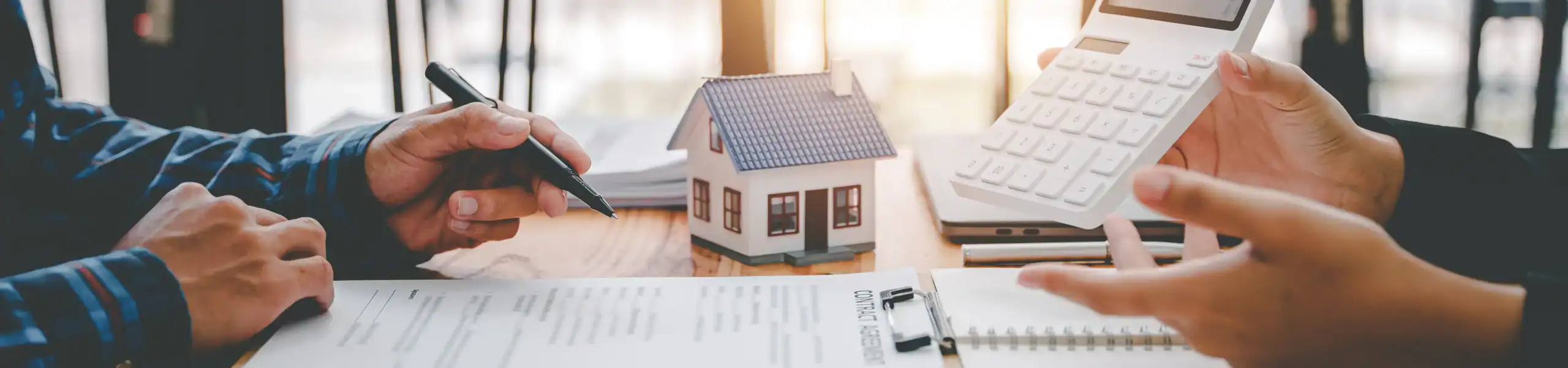 Two people discussing mortgage refinance options with a house model and calculator.