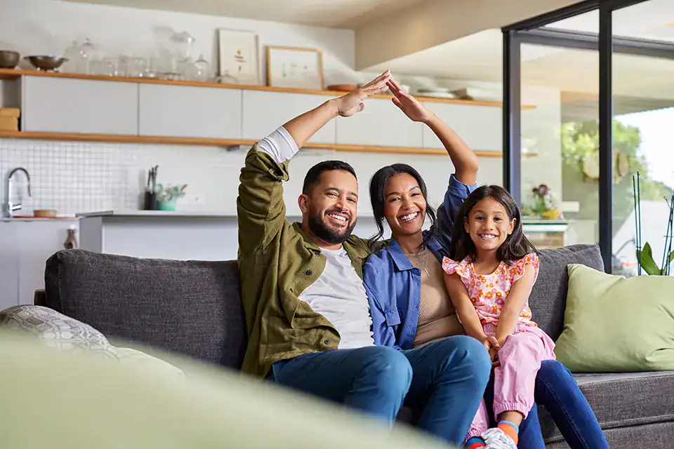 Family sitting on their couch, excited about their mortgage that helped them get their home.