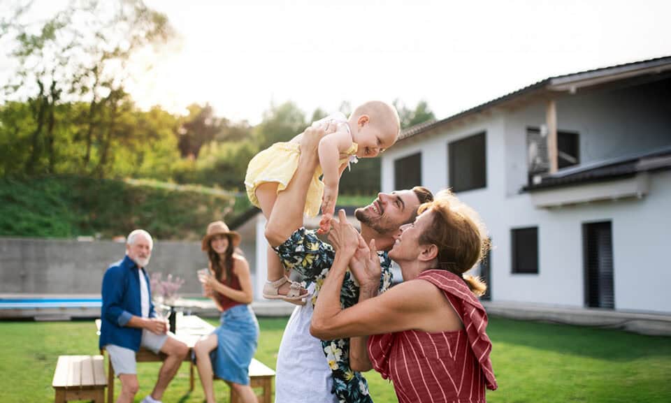Family playing with child in a sunny outdoor setting.