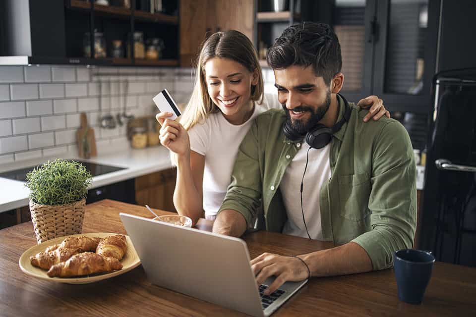 couple with debit card looking at laptop