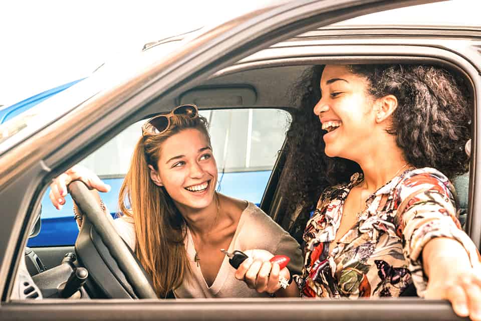 Two women sit in a car smiling