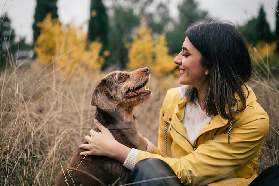 Woman sits and smiles at her dog